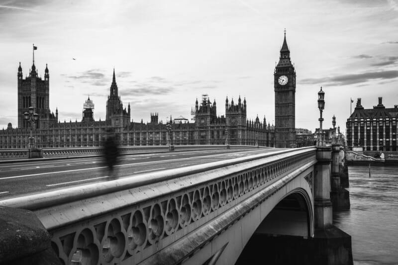 a london bridge with houses of parliament in distance