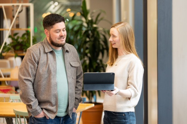 Two people talking over a tablet