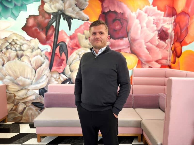 Picture of Tom McDanell, Managing Director at ForrestBrown, against a floral mural backdrop.