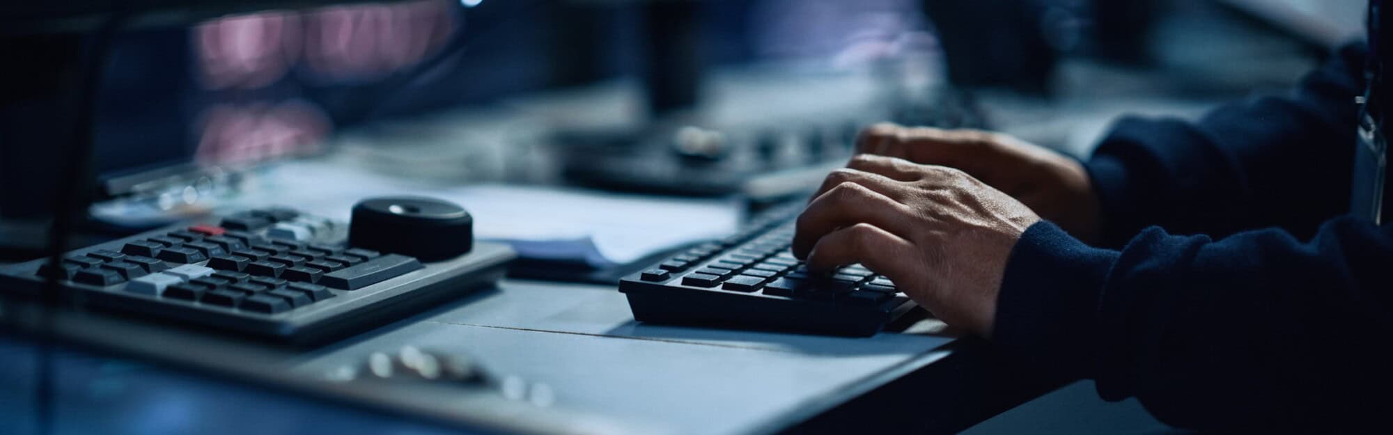 Close up of a professional office specialist working on desktop computer in technological monitoring control room with digital Sscreens. Manager typing on keyboard and using mouse.